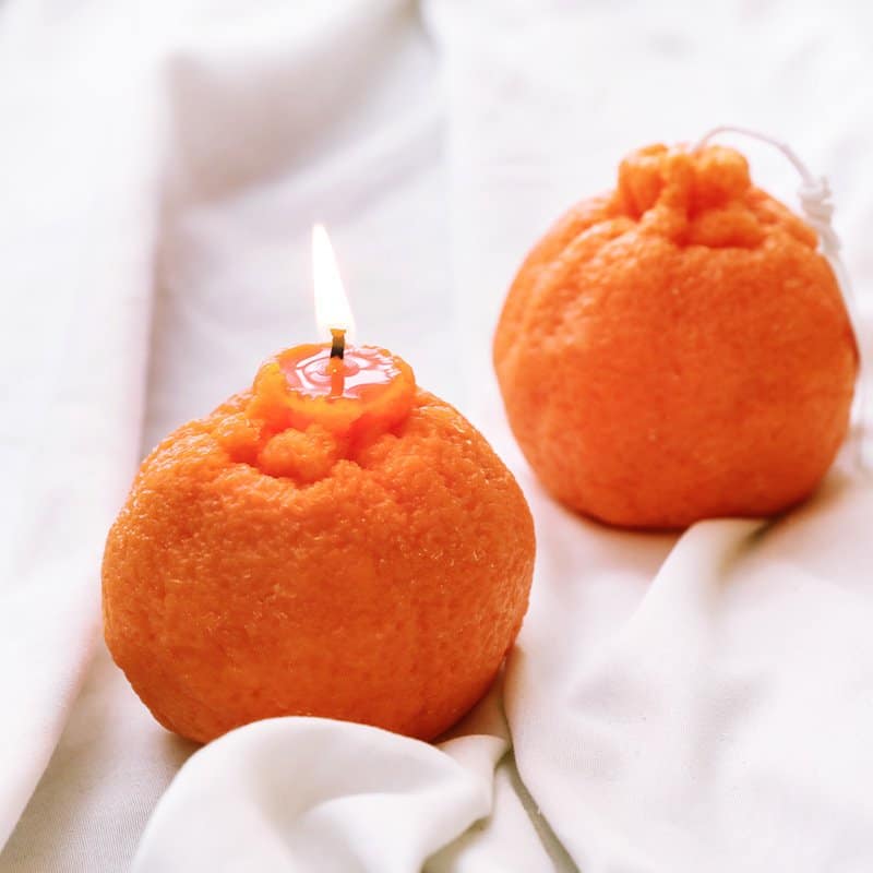 Два Ароматни свещ - портокал седят върху бял чаршаф.